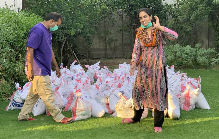 Photo: image of bags of donations gathered and distributed by URI members during the COVID-19 pandemic with two people