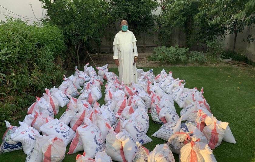 Photo: image of bags of donations gathered and distributed by URI members during the COVID-19 pandemic with man in middle