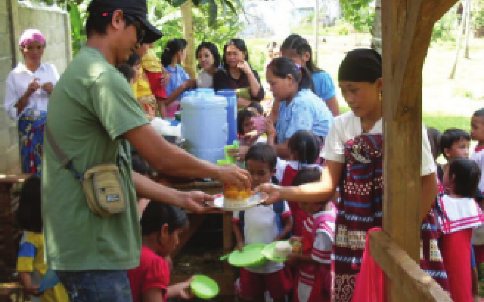 A young man is passing out food to children