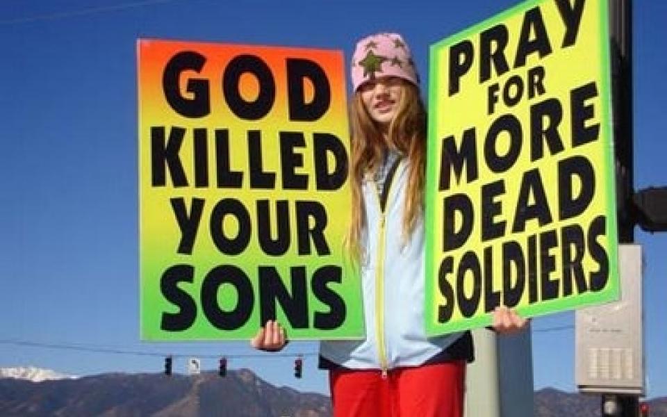 A young girl is holding two posters condemning violence