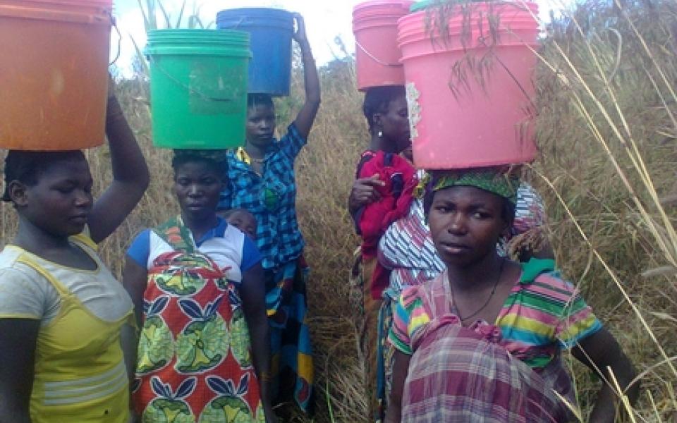 women holding container water on their heads 
