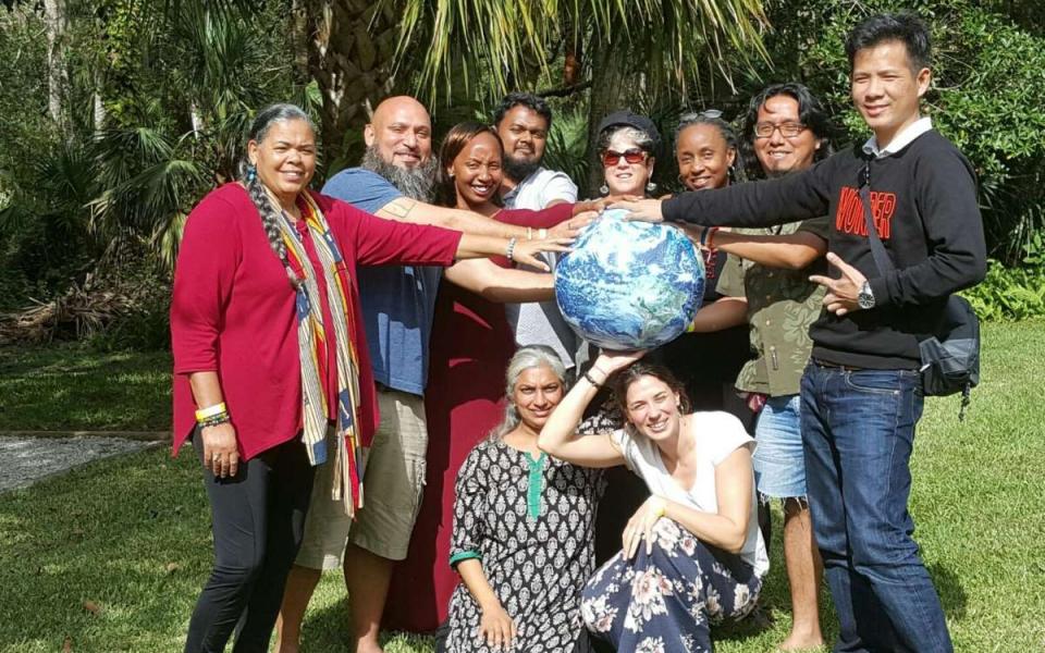 Baraza members standing all together with their hands on a globe