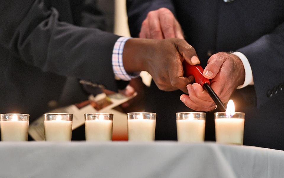 Image Description: Group of different faiths lighting one candle