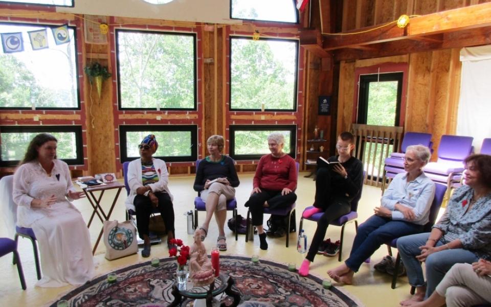 Women sit in chairs around a goddess statue. 