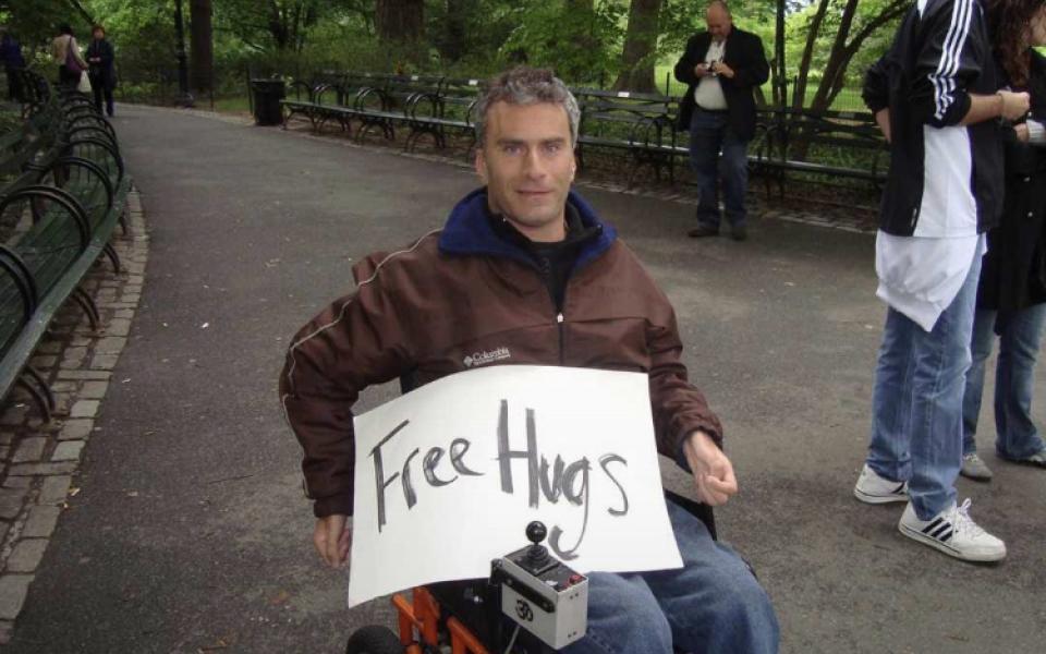 Photo: Gabriel on his wheelchair with a paper written free hugs