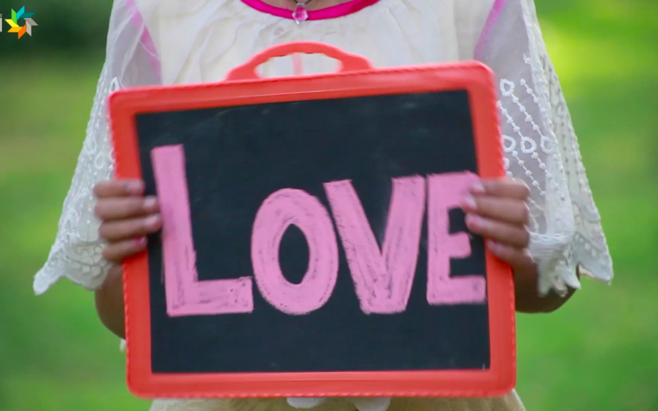 A person holding a slate with 'Love' written on it.
