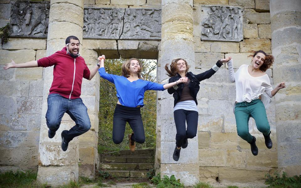 group of young people holding hands and jumping while smiling